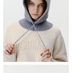Detail of grey knitted balaclava with drawstring and 3D letter embroidery on beige hoodie