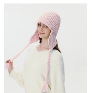 Detail of pink cable knit earflap hat with soft wool texture and braided tassels