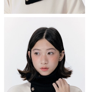 Close-up of cream knit neck warmer with black contrast collar and button details
