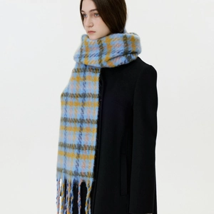 Blue and yellow plaid houndstooth scarf with tassels on a model in a black wool coat