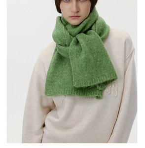 Macro detail of grass green wool knit scarf showing thick ribbed texture and soft fabric