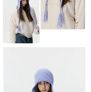 Detail of lavender knit earflap hat featuring thick cable textures and tassel braids