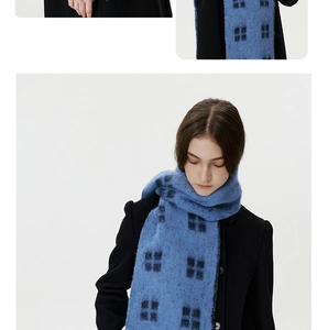 Close-up of soft blue and black checkered wool scarf with warm fringe texture