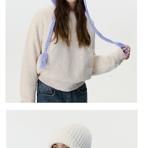 Detail of light purple cable knit beanie with long braided straps and beige sweatshirt