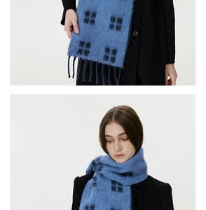 Detail of blue plaid wool scarf with tassels paired with a stylish black winter coat