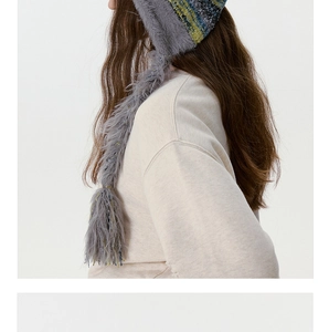 Détail d'un bonnet en maille épaisse grise avec de longs glands et doublure polaire