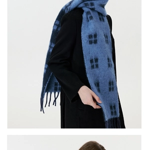 Close-up of blue plaid wool scarf with tassel detail worn with a black winter coat