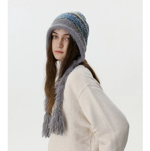 Détail du bonnet en tricot avec doublure en fausse fourrure grise et longs glands à franges