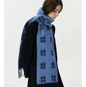 Detail of blue and black plaid wool scarf featuring soft fringe and thick winter texture