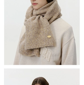 Detailed macro view of beige wool blend knit scarf with oval gold metal logo tag