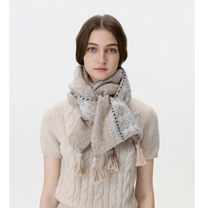 Detail of wool blend Fair Isle knit scarf featuring soft tassels and floral pattern