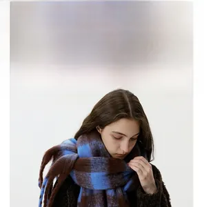 Detail of blue and brown checkered scarf with fuzzy mohair texture and warm tassel ends