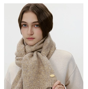 Detail of wool blend knitted scarf texture with premium gold oval logo plaque