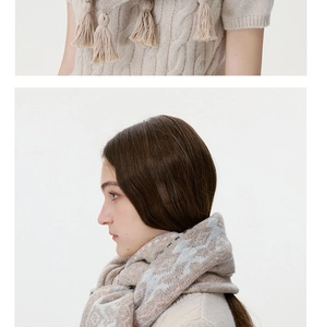 Close-up of oatmeal wool blend knitwear with tassel detail and vintage patterned scarf