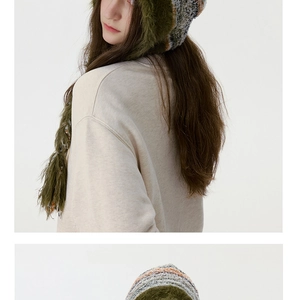 Détail du bonnet en maille rayée multicolore avec bordure en fourrure verte et glands