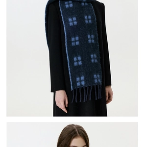 Close-up of a blue plaid wool scarf with long tassels paired with a black wool coat