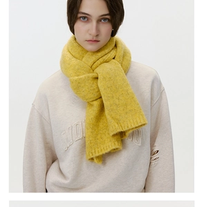 Detailed view of bright yellow wool knit scarf with ribbed texture on a model