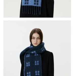 Detail of dark blue plaid wool scarf featuring thick tassels and soft brushed texture