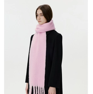 Nahaufnahme eines rosa Wollschals mit dicken Fransen getragen über einem schwarzen Mantel