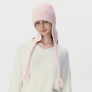 Pink knit trapper hat with ear flaps and braided tassels on a studio model