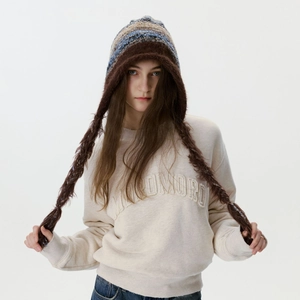 Bonnet en tricot avec tresses et pompons assorti à un sweat-shirt brodé beige d'automne