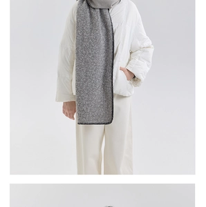 Detail of grey knitted wool scarf with black stitched edges over white down jacket