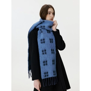 Blue plaid wool blend scarf with fringe worn by a model in a black winter coat