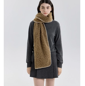 Detail of caramel brown cashmere-like scarf with white whipstitch edges on a model