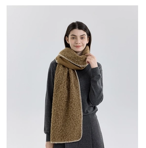 Detail of brown wool-like scarf showing thick loop yarn texture and white stitched edges