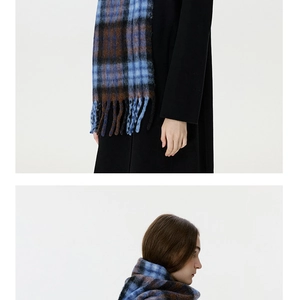Detail of blue and caramel plaid scarf featuring long tassels and soft wool texture