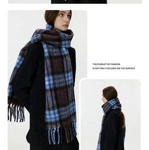 Detail of blue and brown plaid scarf featuring thick tassels and soft wool-like texture