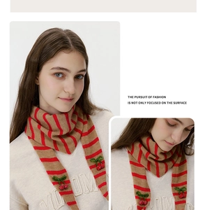 Detail of red and brown striped wool knit scarf with cherry and bow accents