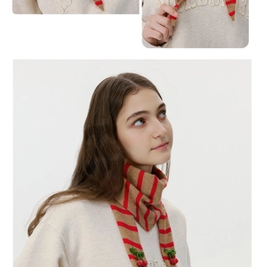 Detail of red striped knit neck scarf featuring 3D cherry accents and leaf decoration