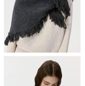 Detailed texture of charcoal grey wool knit shawl with fringe on light sweatshirt