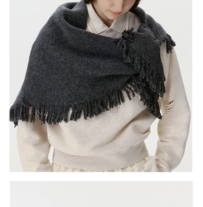 Close-up of dark grey wool blend knit shawl featuring dense tassel fringe edges