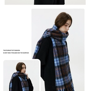 Detailed view of the soft blue and brown plaid scarf featuring thick tassels and cozy texture
