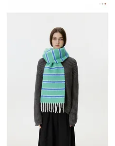 Detail of wool blend knit scarf featuring mint green and royal blue stripes with white tassels