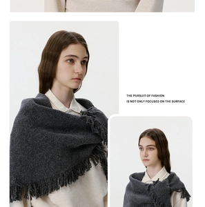 Close-up of dark grey knitted wool shawl showing fringe details and thick texture