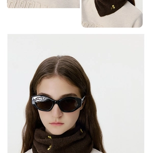 Detail of soft brown knitted scarf featuring delicate yellow flower embroidery texture