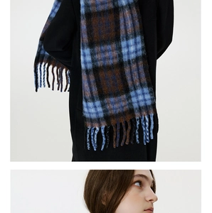 Detail of blue and brown plaid scarf with thick twisted tassels and soft wool texture