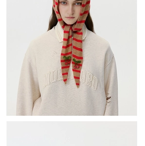 Detailed shot of striped wool knit scarf featuring 3D beaded cherry decor and knit texture