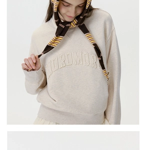 Detailed view of the 3D MOROMOR letter embroidery on a beige cotton knit sweatshirt