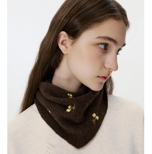 Detailed macro view of yellow floral embroidery on soft dark brown knitted neck warmer