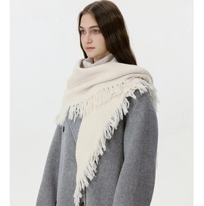 Detail of soft cream wool-blend knit scarf with fine tassel fringe on grey winter coat