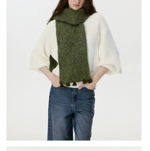 Close-up of grass green wool blend knitted scarf featuring soft fringe details and fluffy texture