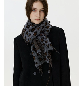 Close-up of leopard print knitted scarf with tassels paired with a black double-breasted coat