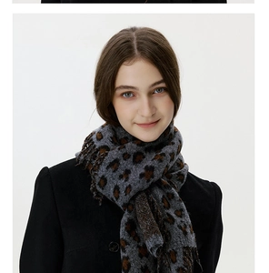 Close-up of leopard print knitted scarf with fringe, paired with a black wool coat
