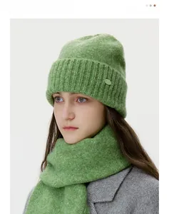 Detail of green knitted earflap beanie and neck warmer set with warm fuzzy texture