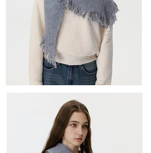 Detail of soft wool knitted scarf featuring long tassel fringe in elegant charcoal grey