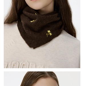 Detail of wool knit neck warmer with delicate yellow floral embroidery on dark brown fabric